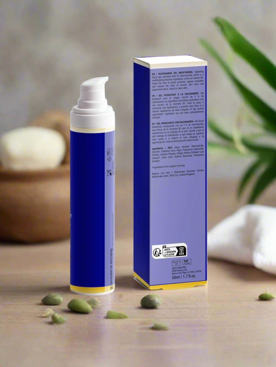 Blue skincare product bottle and box on a wooden surface with green leaves in the background